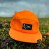 Vöks Outdoor orane 5-panel cap surrounded by cloudberries.