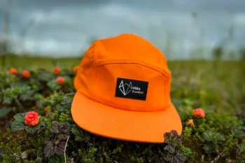 Vöks Outdoor orane 5-panel cap surrounded by cloudberries.